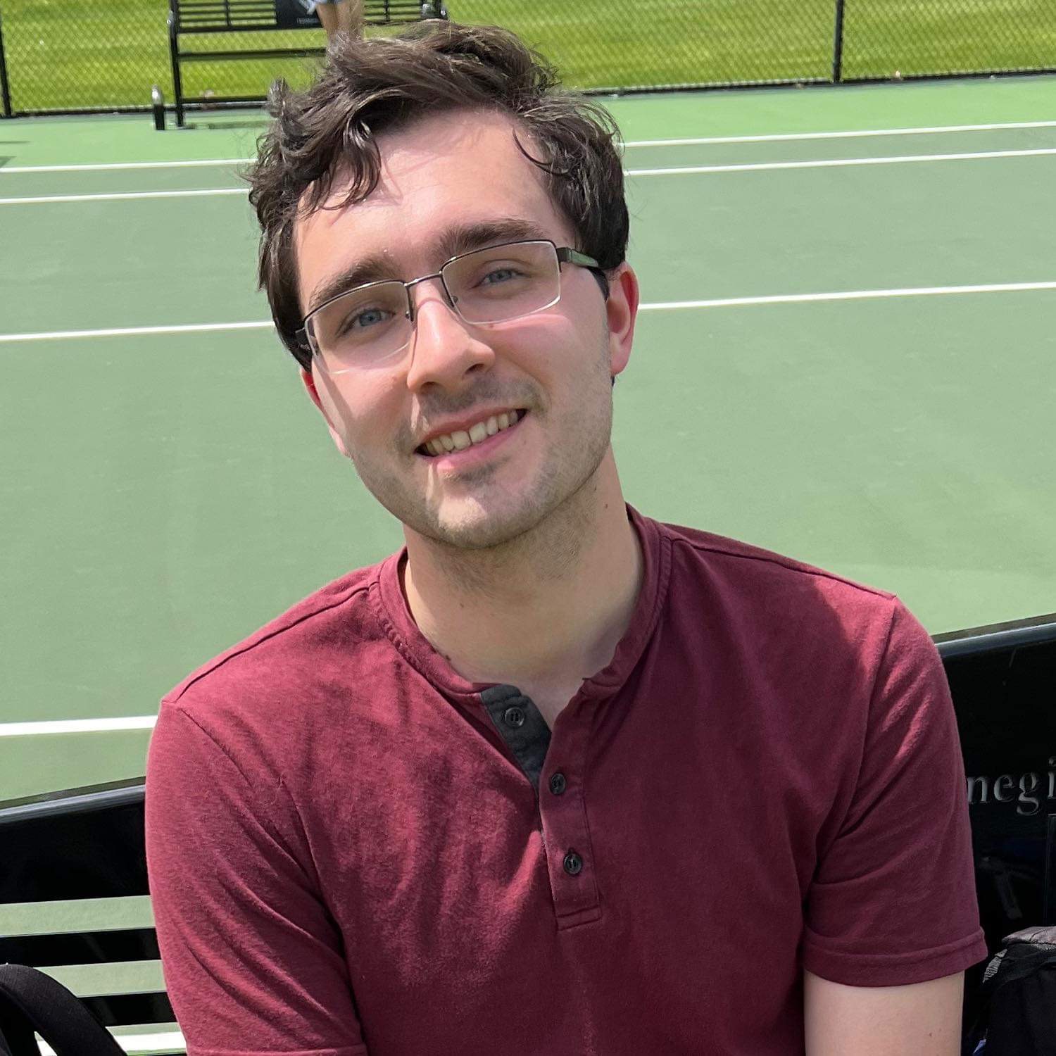 Headshot of a man standing on a tennis court