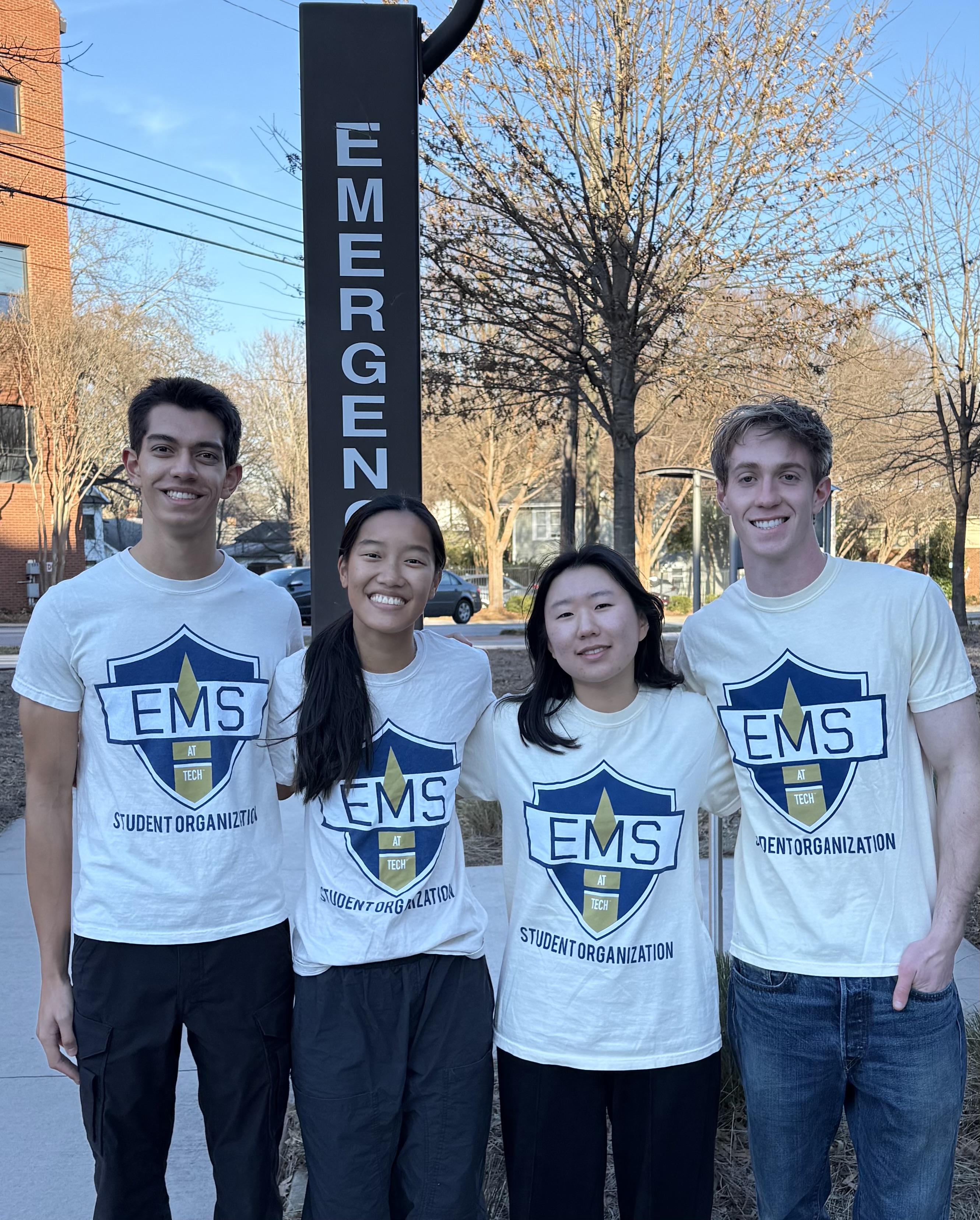Four students stand in front of emergency sign.