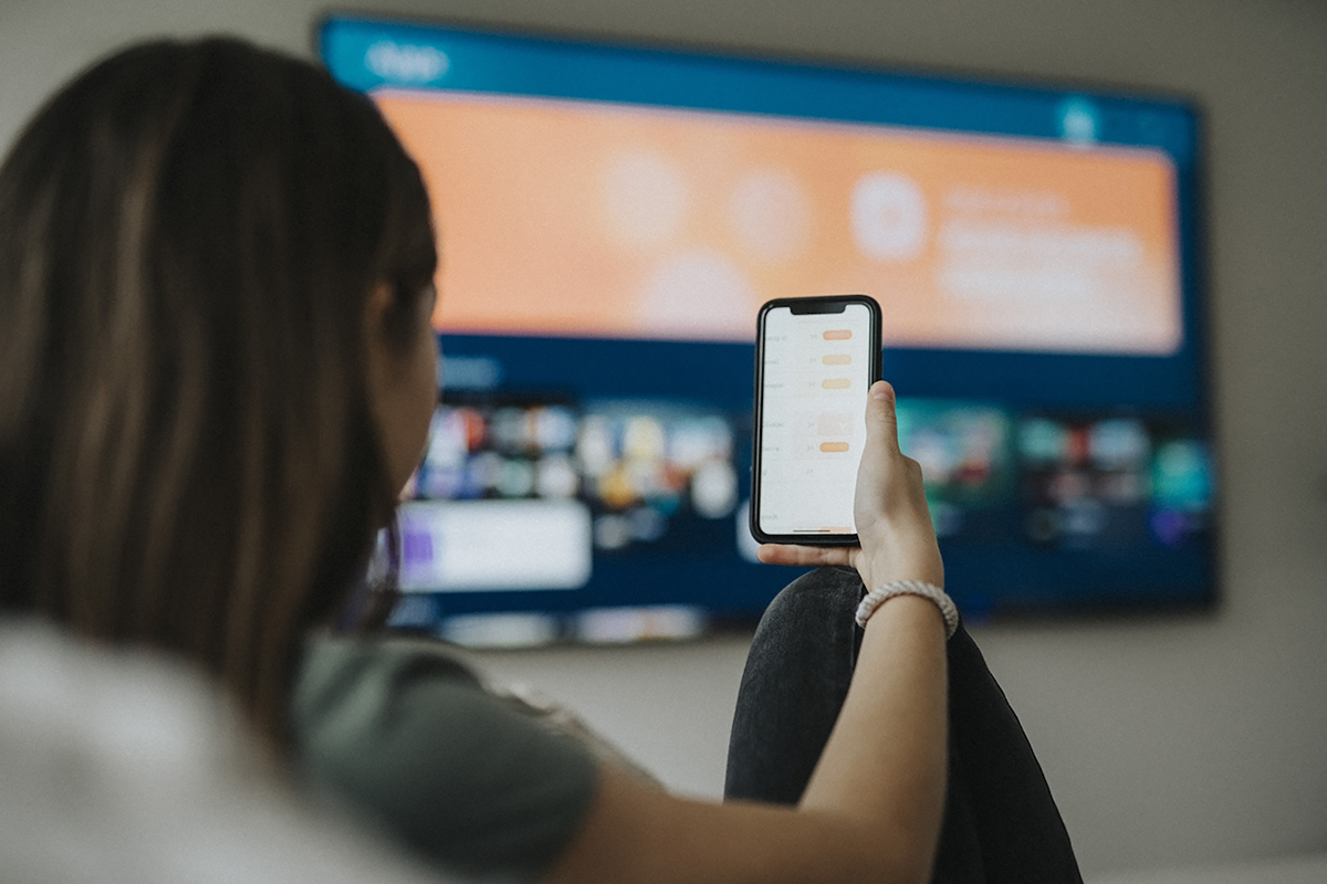 A person holds a cell phone while watching television.