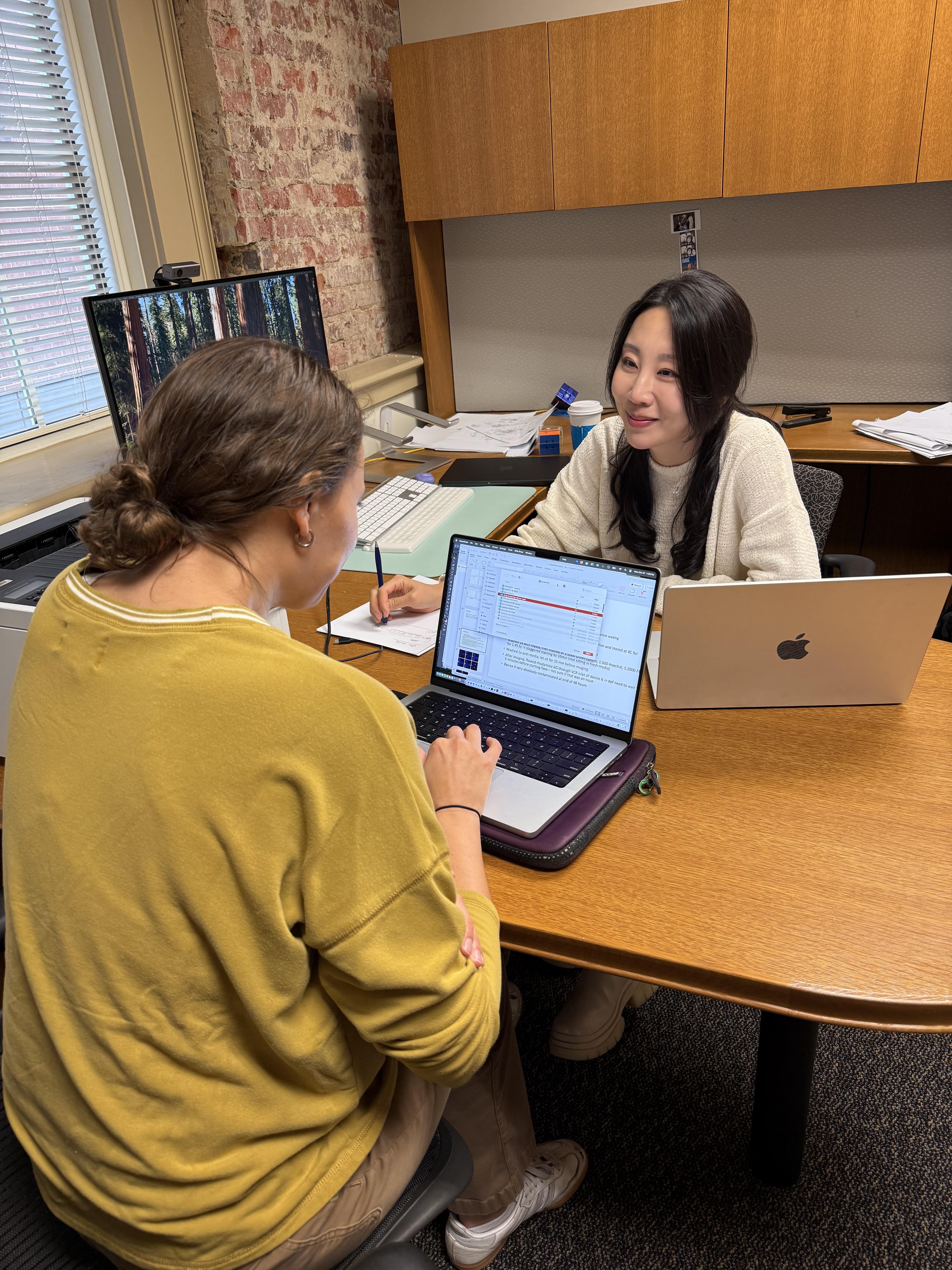 A student and woman confer at a desk.