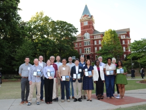 Faculty and staff honorees hold their awards during a group photo in front of Tech Tower 