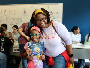 Young author Soleil A. Cross holds her book, Pluto, Special, Just the Same Dwarf Planet, as she explores the Brain Games exhibit with her mom.