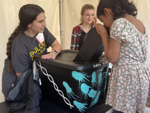 Microbiology Ph.D. student Iris Irby shows attendees glowing bacteria at an Exploration Expo booth hosted by the Center for Microbial Dynamics and Infection. (Photo Jess Hunt-Ralston)