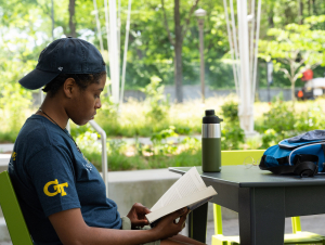 Student reading Woman reading a book outside The Kendeda Building.