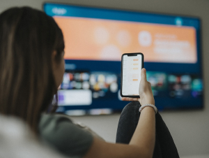 A person holds a cell phone while watching television.