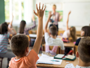 kids raising hands in classroom